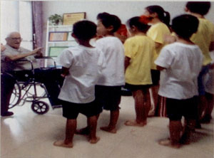 Un grupo de niños cantan el cumpleaños feliz al padre Luis.