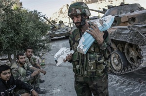 Un soldado en Maalula lleva en sus manos <br>los restos de una imagen de la Virgen.