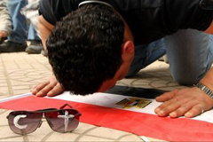 Un musulmán, con la cruz y la media luna en sus gafas de sol, reza sobre una bandera egipcia.